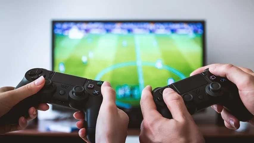 Dos pesonas juegan con la videoconsola PS4 a un videojuego FIFA. (Foto: Wikimedia)